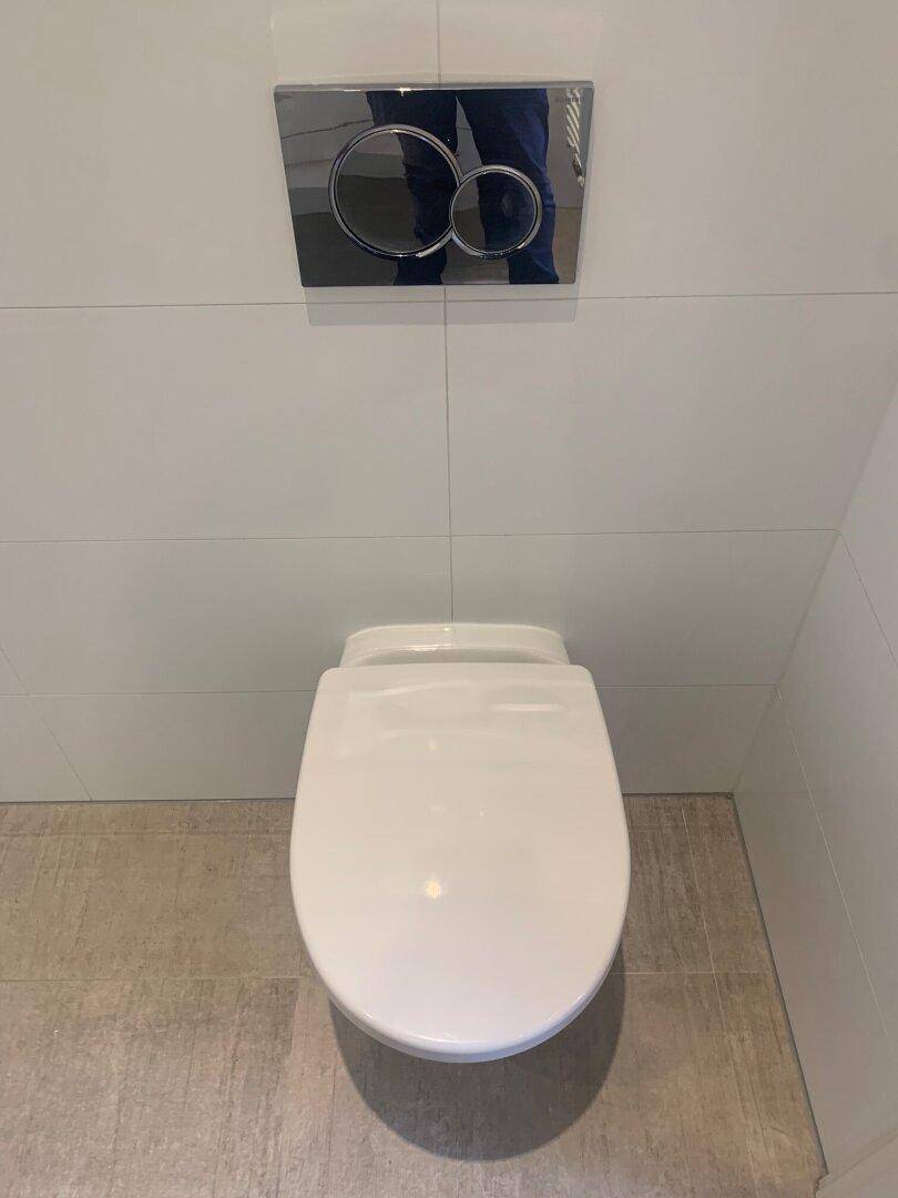 Wandhängendes WC mit moderner Spülplatte und Fliesenboden.