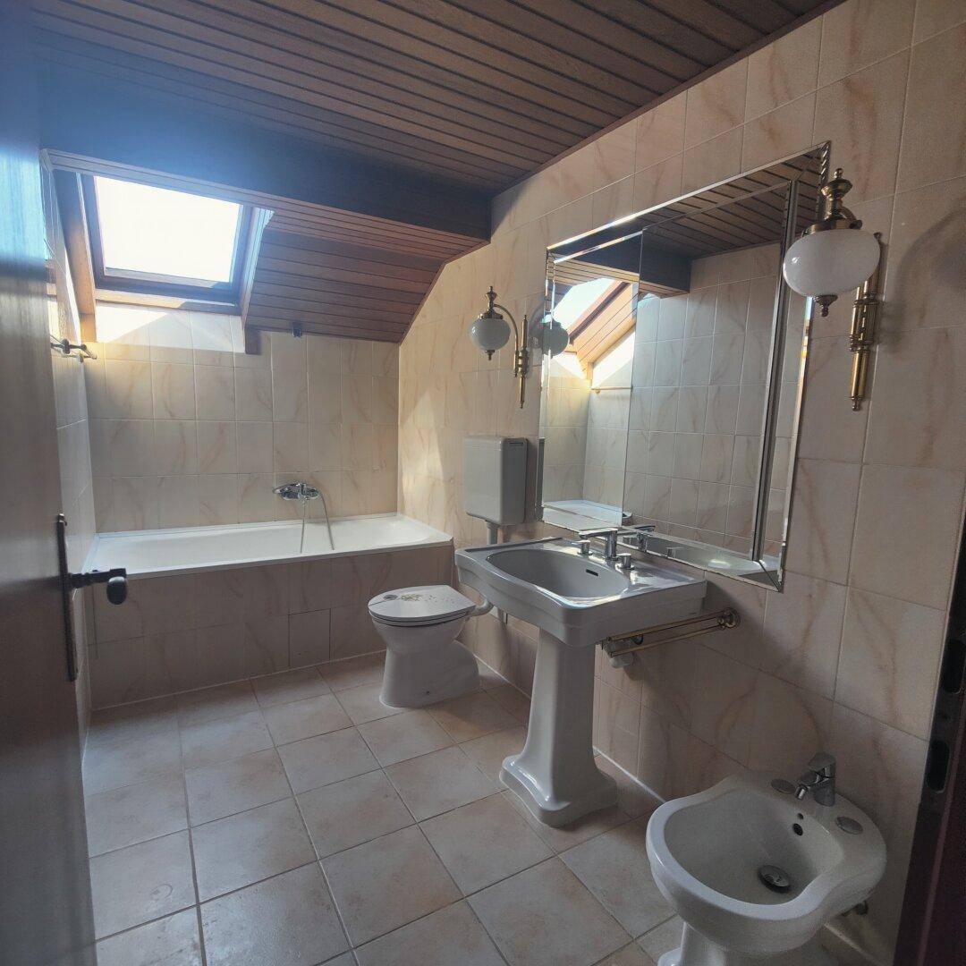 Helles Badezimmer mit Badewanne, Standwaschbecken, Bidet und Dachfenster unter Holzdecke.