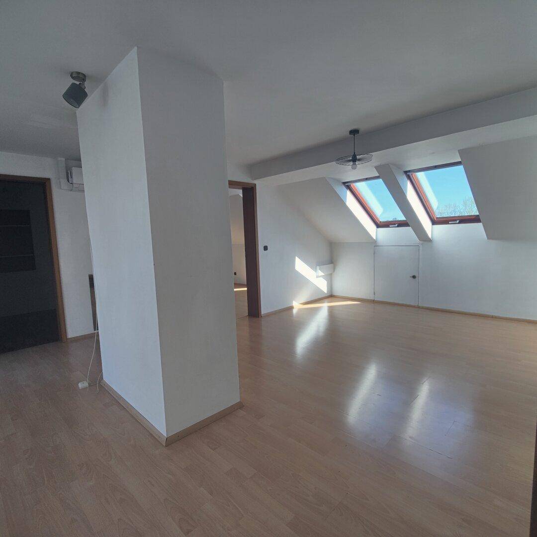 Geräumiger, heller Raum im Dachgeschoss mit schrägen Wänden und zwei großen Dachfenstern.