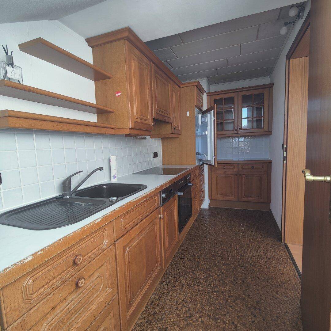 Klassische Holzküche mit weißen Fliesen als Spritzschutz und praktischen Regalen für Utensilien.