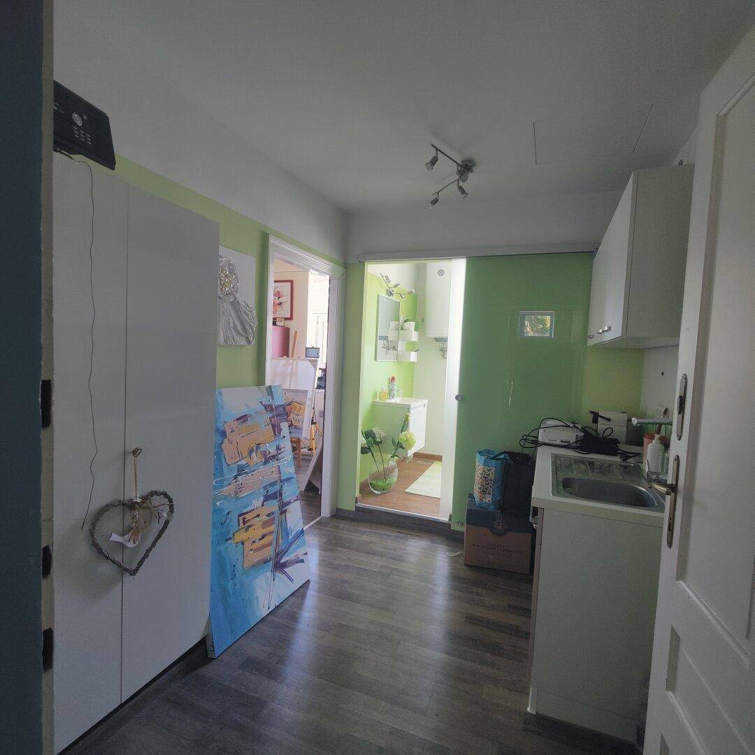 Flur mit Stauraum und Waschmaschine, der zu einem modern gestalteten Badezimmer führt.