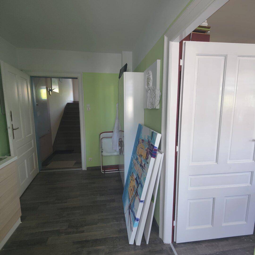 Heller Flur mit grün gestrichener Wand und Blick auf das Treppenhaus, bietet Zugang zu weiteren Räumen.
