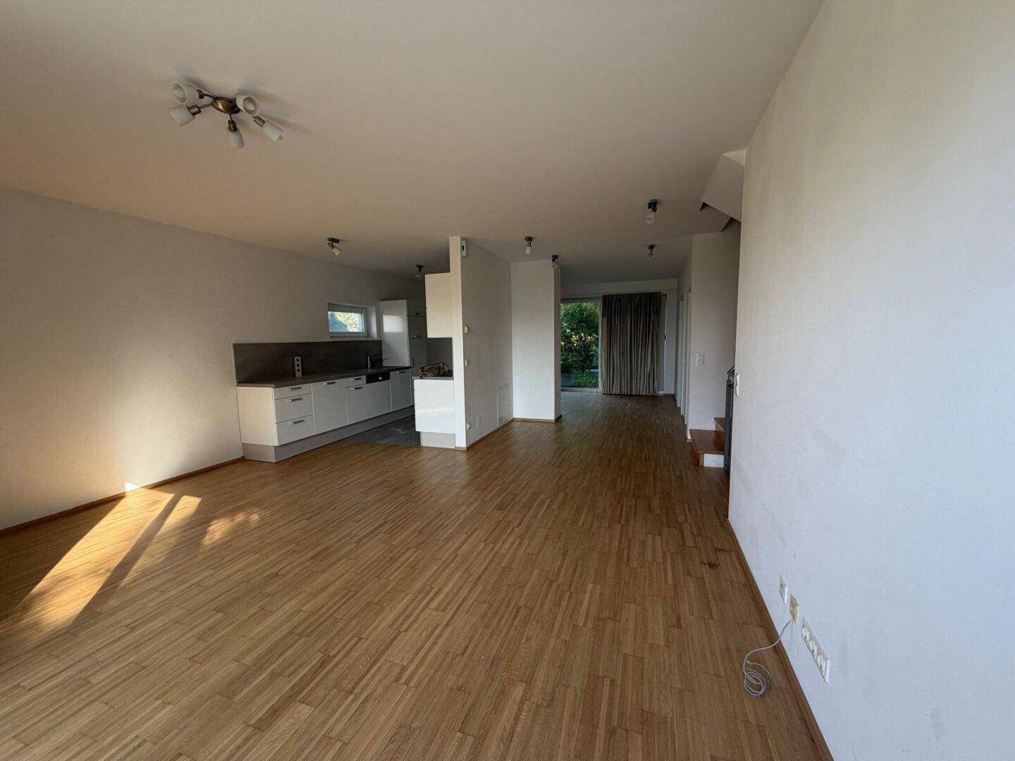 Offener Wohnbereich mit Holzboden und integrierter Küchenzeile, ideal für modernes Wohnen.