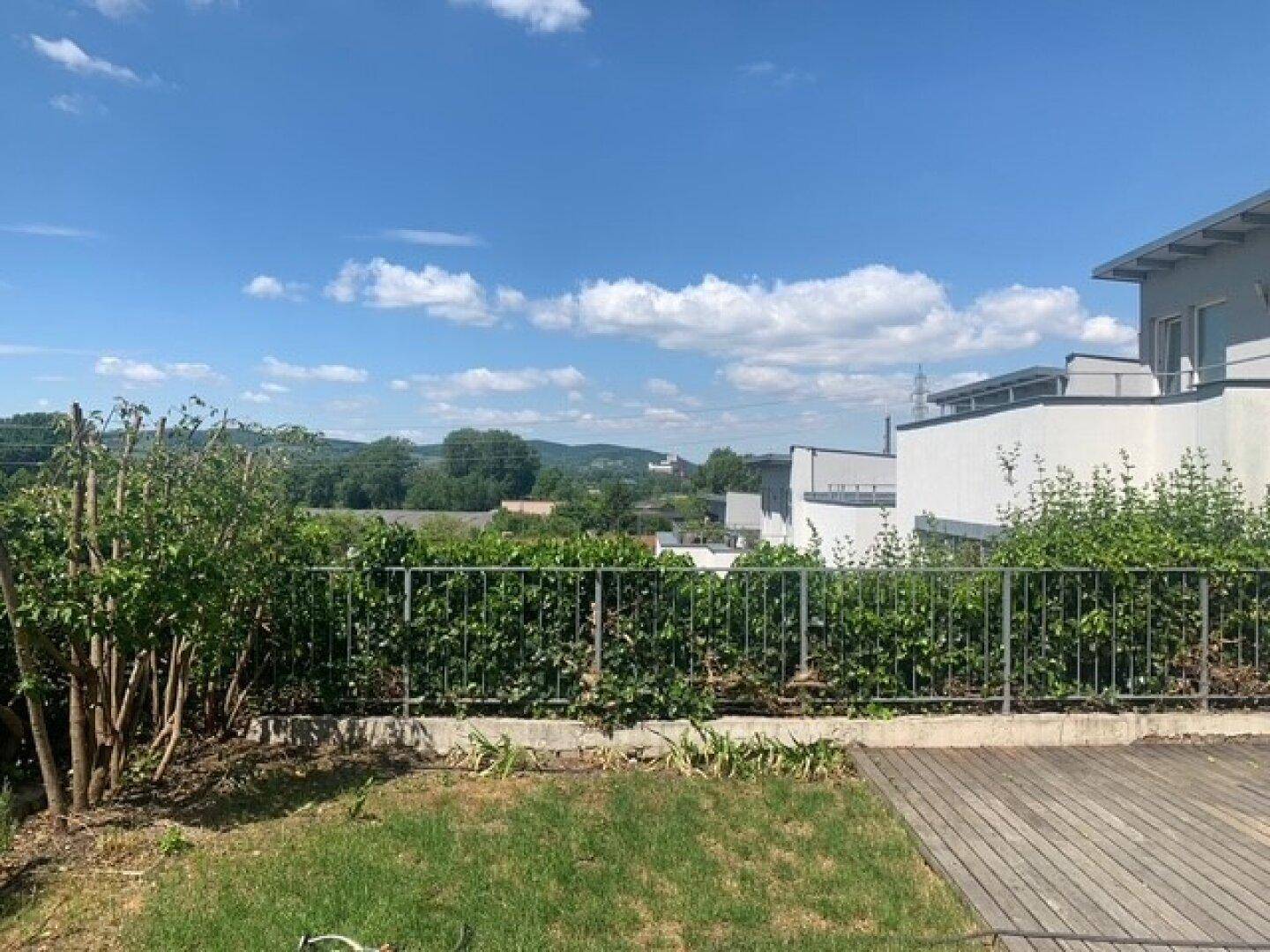Holzterrasse mit Blick auf die üppige grüne Vegetation und die umliegende Landschaft.