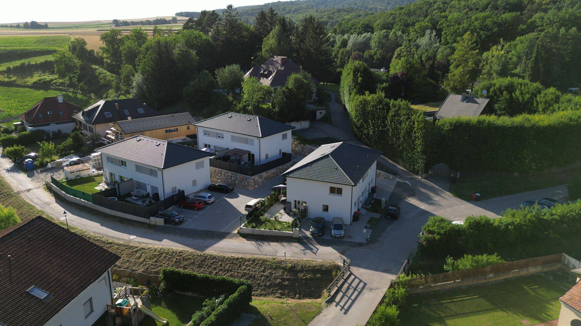 Luftaufnahme einer Wohnsiedlung mit Neubauten, umgeben von grüner Landschaft und Feldern.