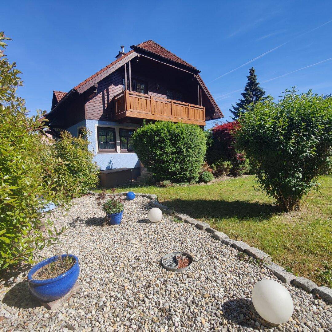 Charmantes Haus mit gepflegtem Garten, Kiesweg und dekorativen Kugelleuchten.