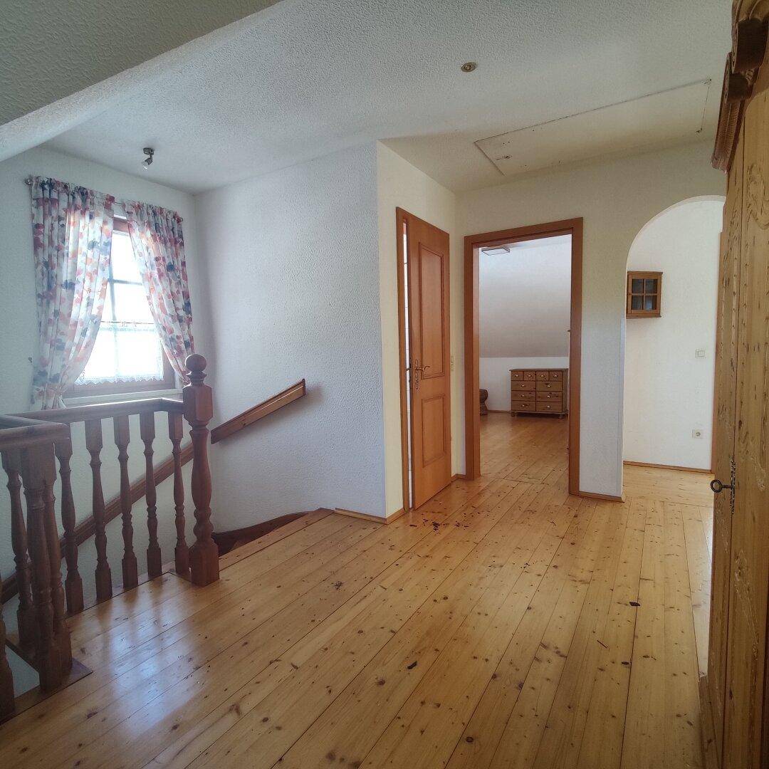 Heller Flur im Obergeschoss mit Holzdielenboden, Fenster und Holzgeländer.
