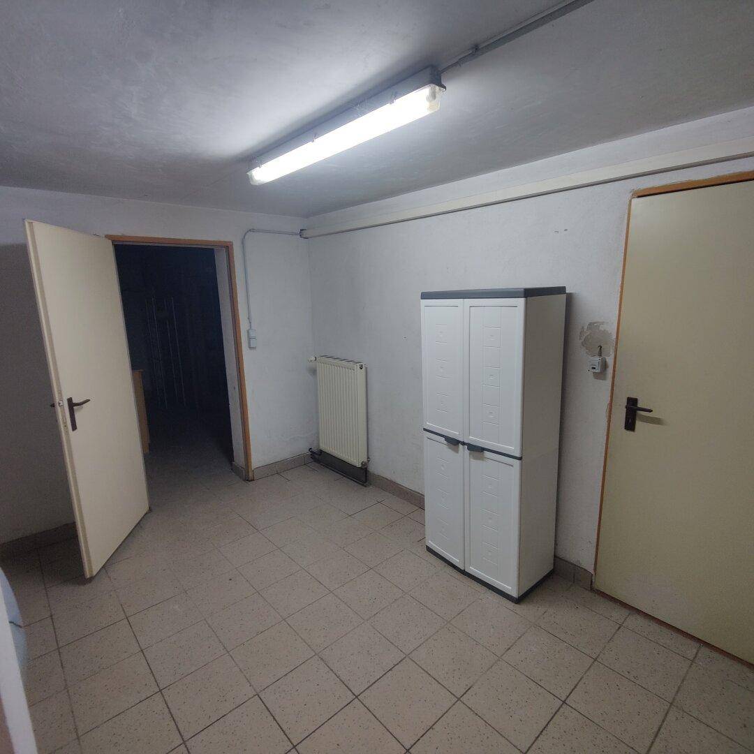 Geräumiger Kellerraum mit Fliesenboden, weiß gestrichenen Wänden und praktischem Stauraum.