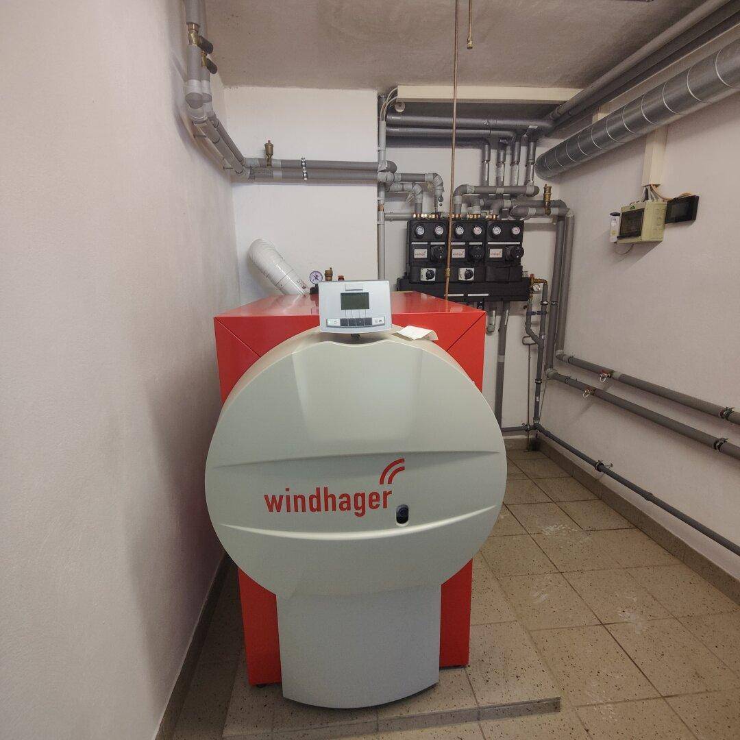 Heizungsraum im Keller mit modernem Windhager-Heizkessel und umfangreicher Verrohrung.