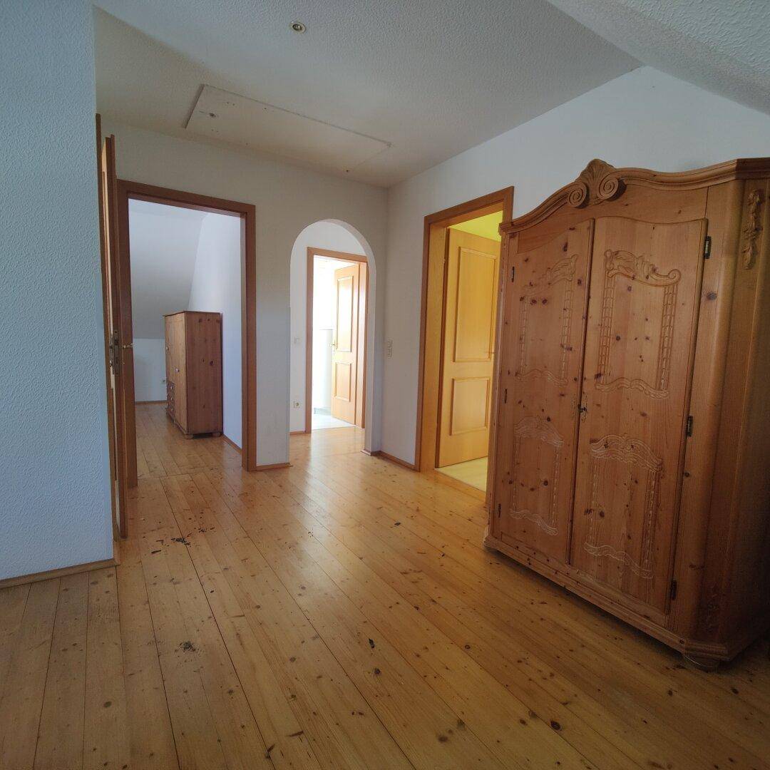 Heller Flur mit Holzdielenboden, einem antiken Holzschrank und Zugang zu weiteren Räumen.