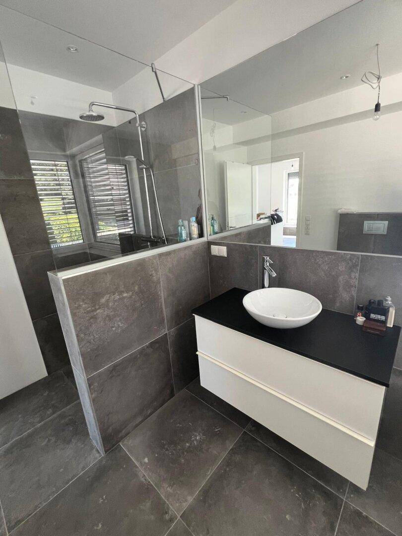 Modernes Badezimmer mit stilvollem Waschtisch, großem Spiegel und begehbarer Dusche.