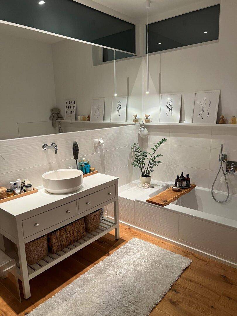 Helles Badezimmer mit Badewanne, modernem Waschtisch und stilvoller Dekoration.