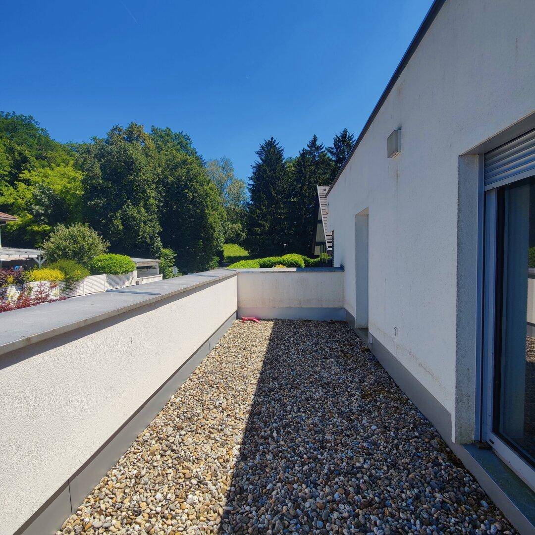 Dachterrasse mit Kiesbelag und Blick auf die umliegende grüne Landschaft.