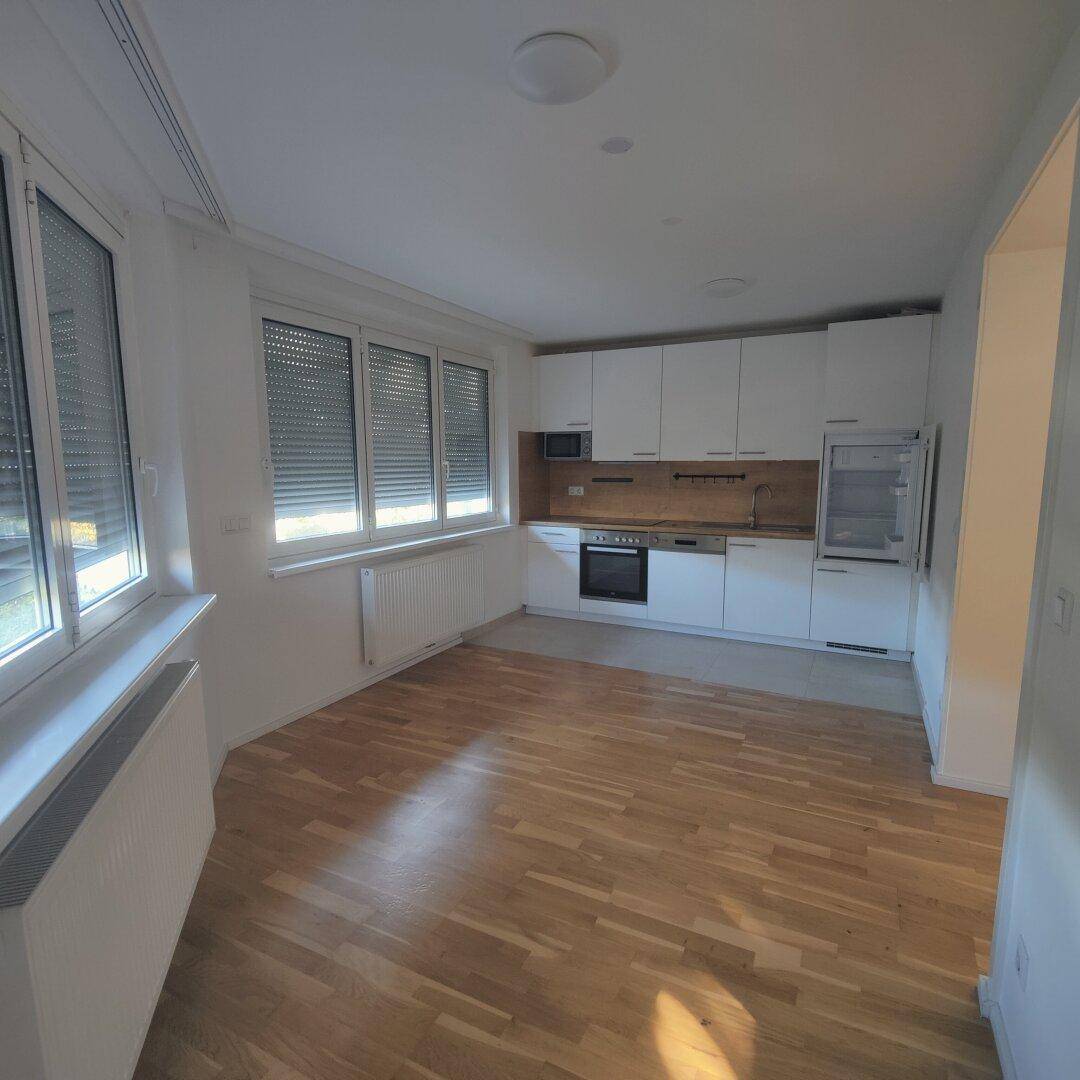Moderne Einbauküche mit weißen Schränken, Holz-Arbeitsplatte und integrierten Geräten.