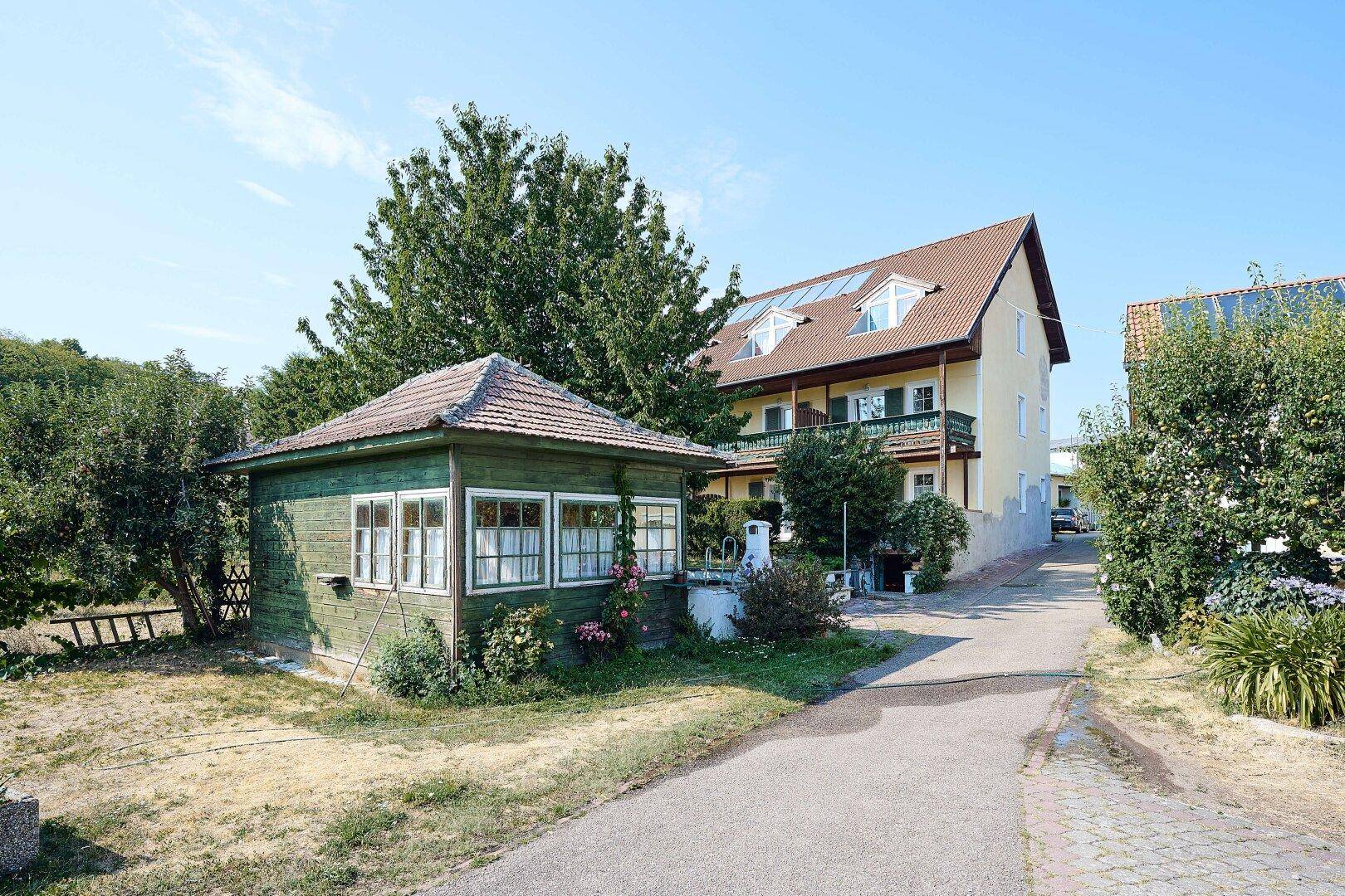 Außenansicht des Hotelgebäudes mit Dachgauben und einem kleinen grünen Gartenhaus im Vordergrund.