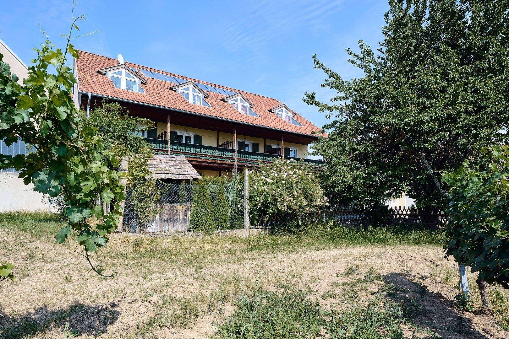 Rückansicht des Hotelgebäudes mit mehreren Dachgauben und einem weitläufigen Gartenbereich im Vordergrund.