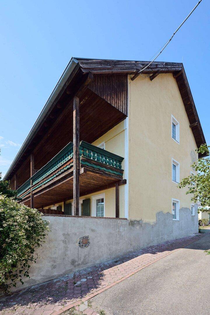 Seitenansicht des Hotelgebäudes mit traditionellen Holzbalkonen und einer gelben Fassade.