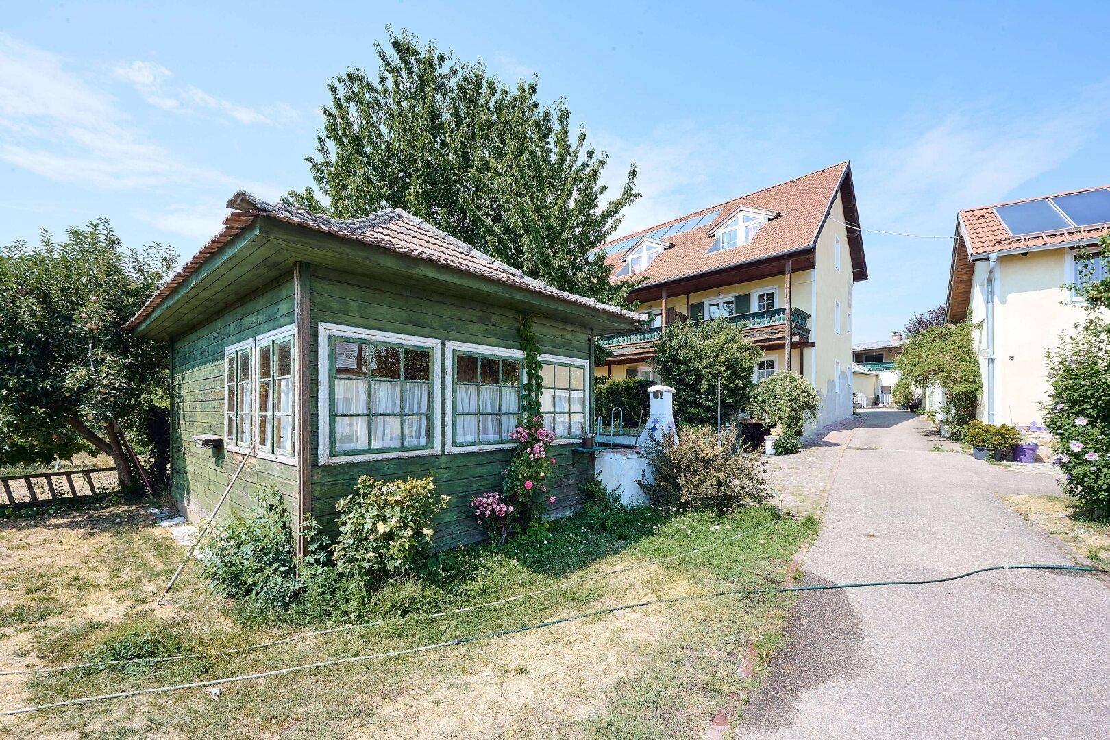 Außenansicht des Hotelgebäudes mit Dachgauben und einem kleinen grünen Gartenhaus im Vordergrund.