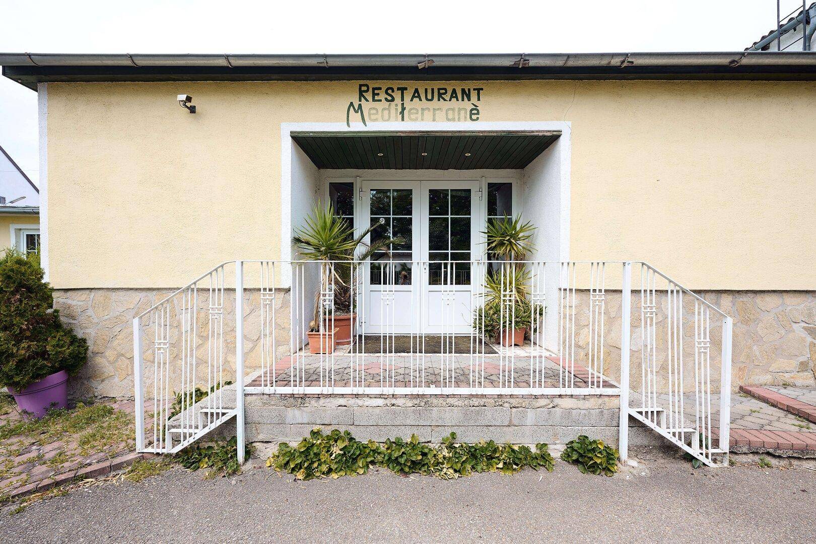 Eingangsbereich des Restaurants "Mediterrane" mit weißen Treppen und Pflanzen in Töpfen.
