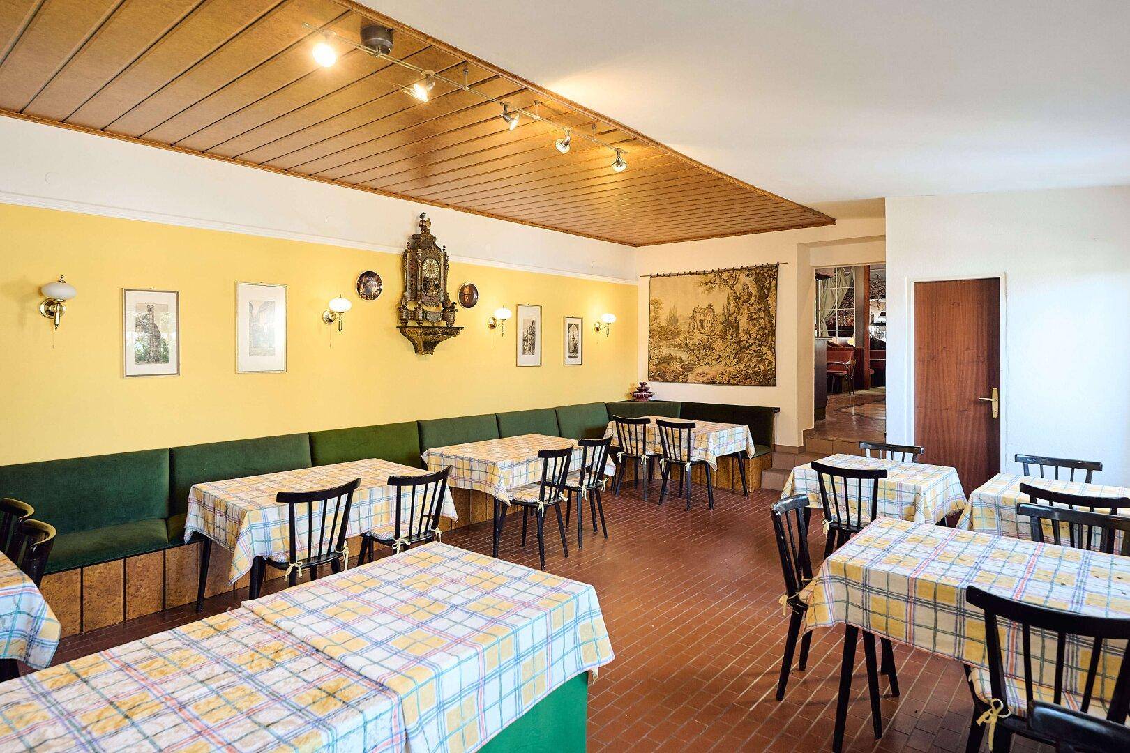 Ein traditioneller Speisesaal mit karierten Tischdecken, Holzbänken und einer Holzdecke.