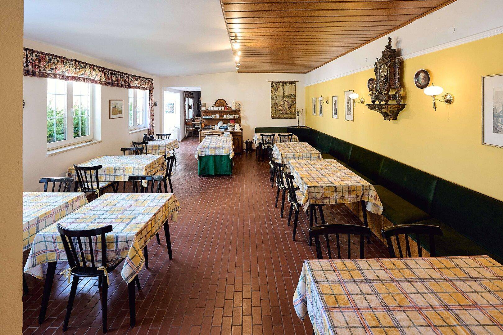 Geräumiger Speisesaal mit traditioneller Einrichtung, karierten Tischdecken und Blick nach draußen.