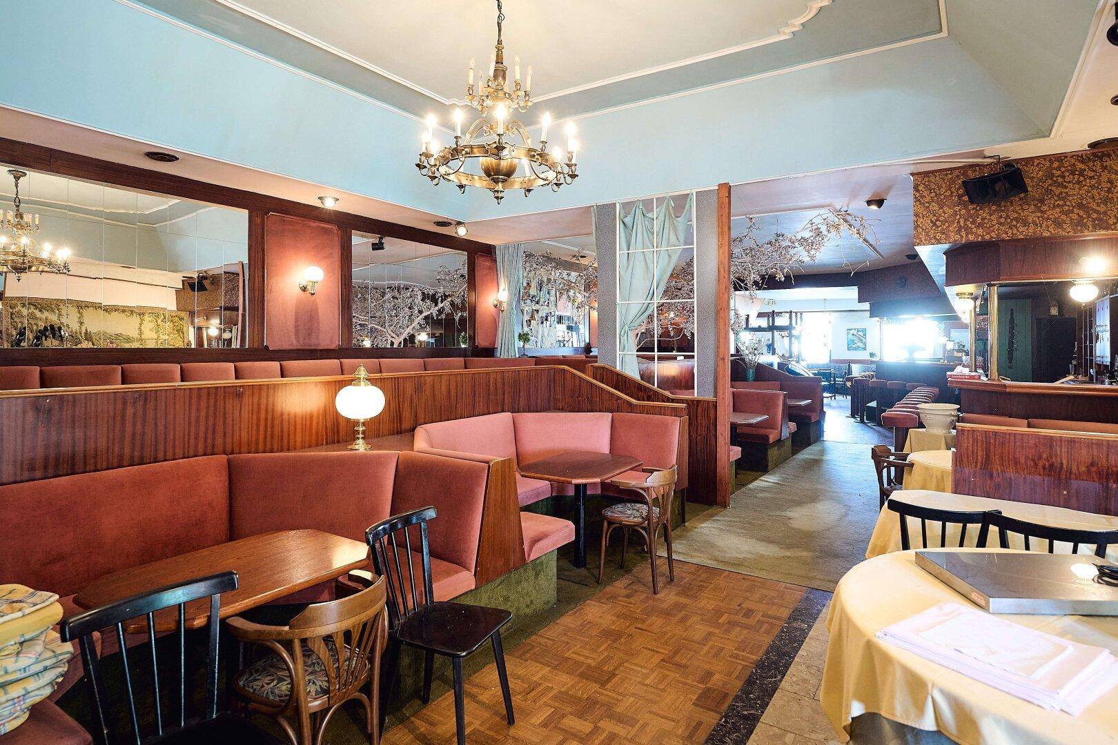 Eine gemütliche Bar-Lounge mit plüschigen Sitzgelegenheiten, Spiegeln und einem Kronleuchter.