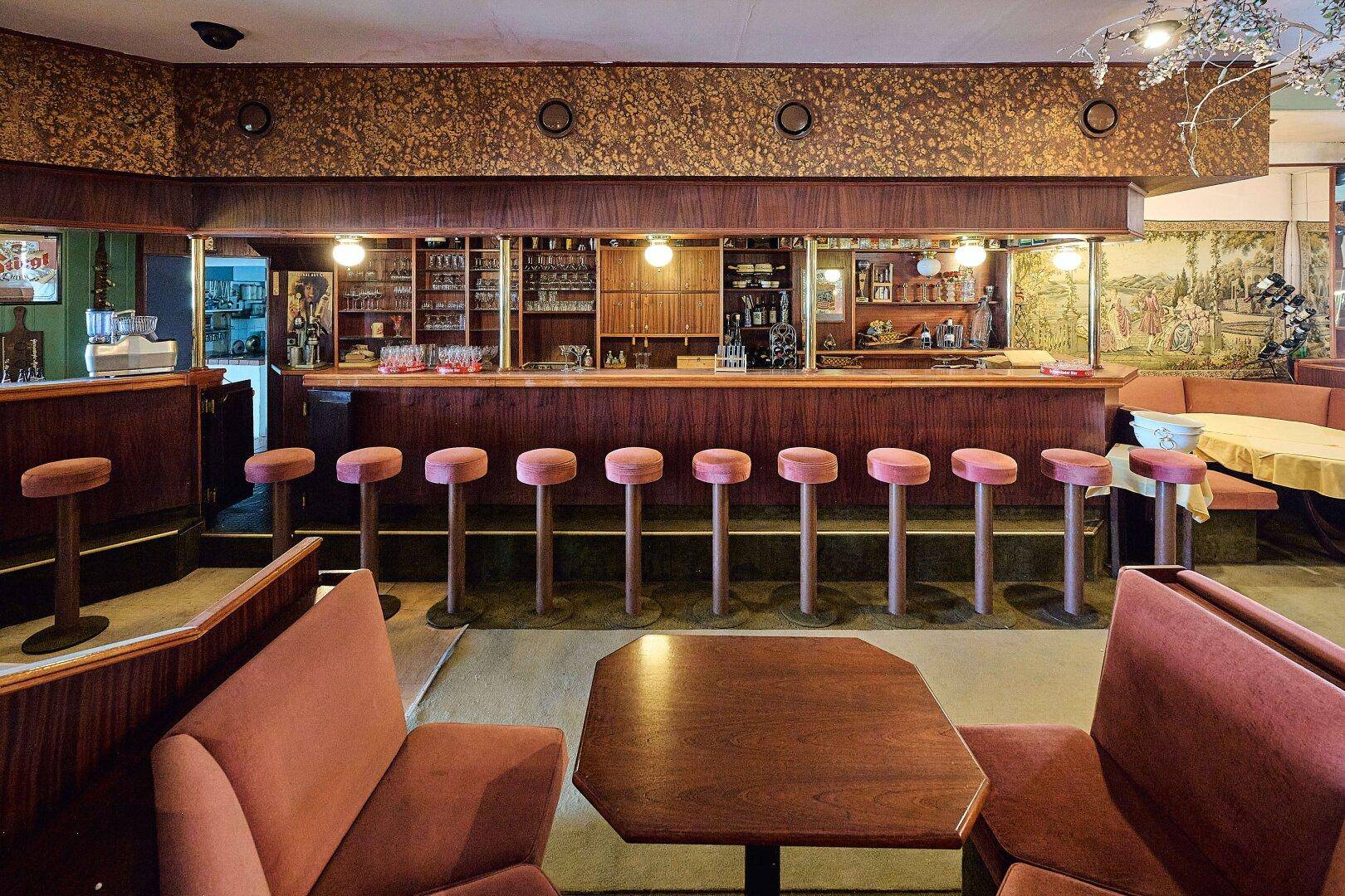 Eine klassische Bar mit Hockern, Holzvertäfelung und einer gut ausgestatteten Theke.
