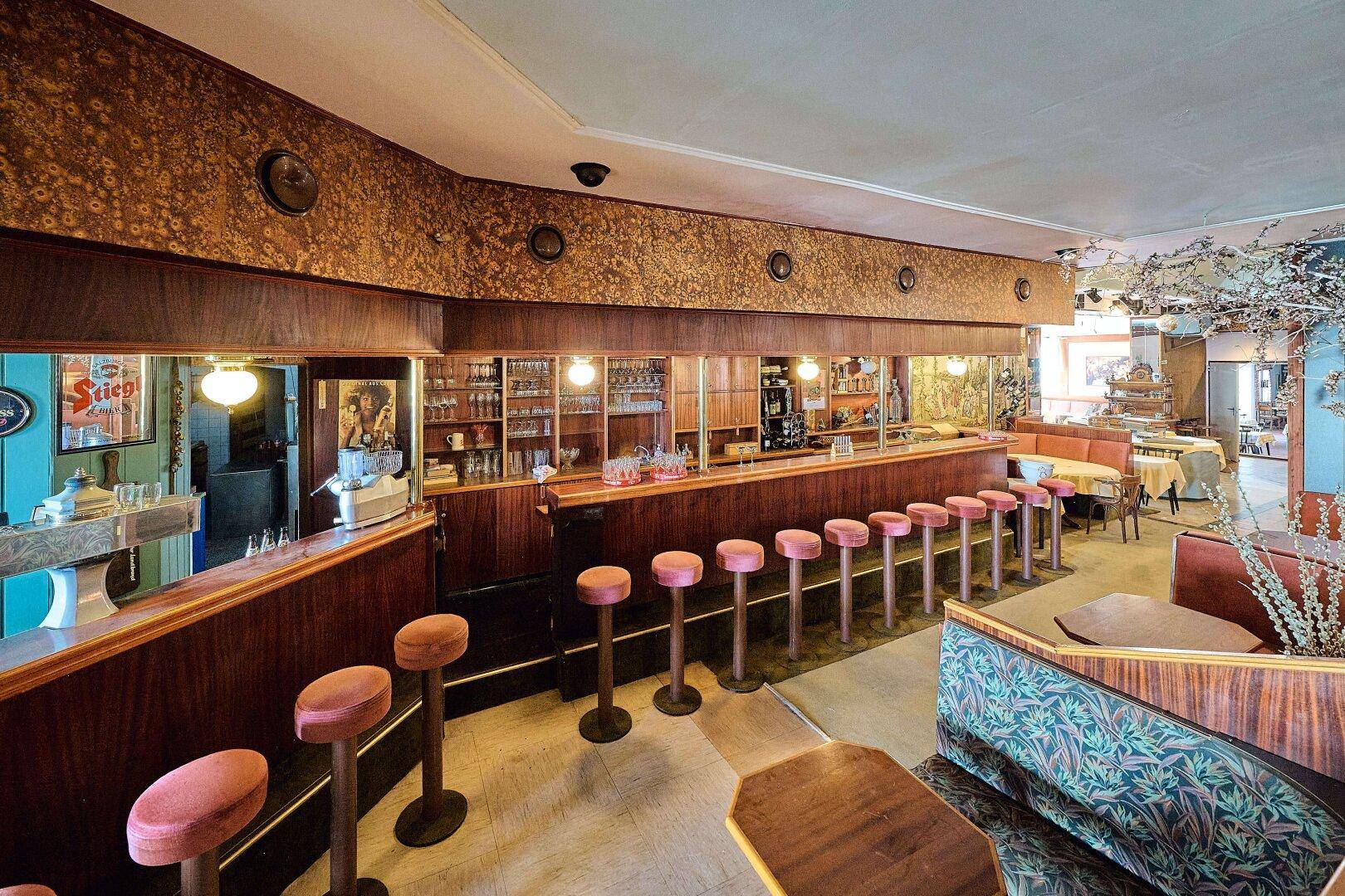 Vintage Bar mit Holzvertäfelung, gepolsterten Hockern und Spiegeln, die eine gemütliche Atmosphäre schaffen.