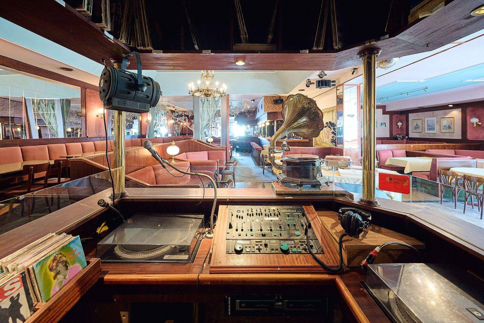 DJ-Pult mit Plattenspieler, Mischpult und einem historischen Grammophon in einem Gastraum.