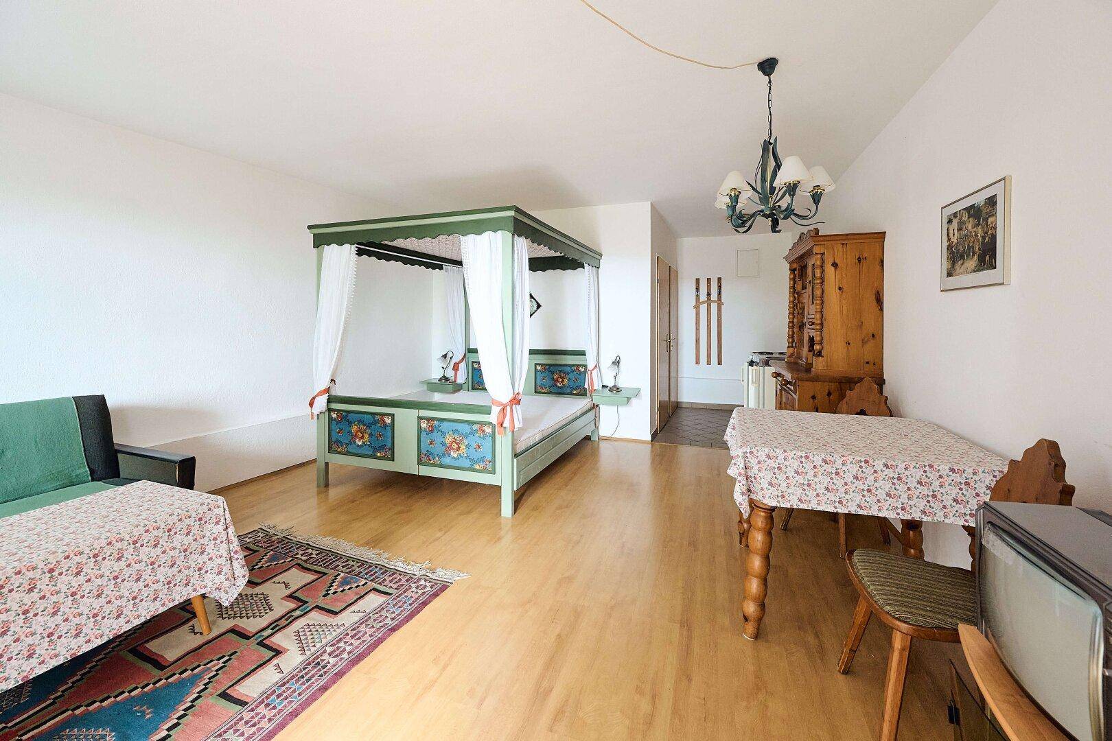 Großes Schlafzimmer mit Himmelbett, Esstisch und traditionellen Holzmöbeln.