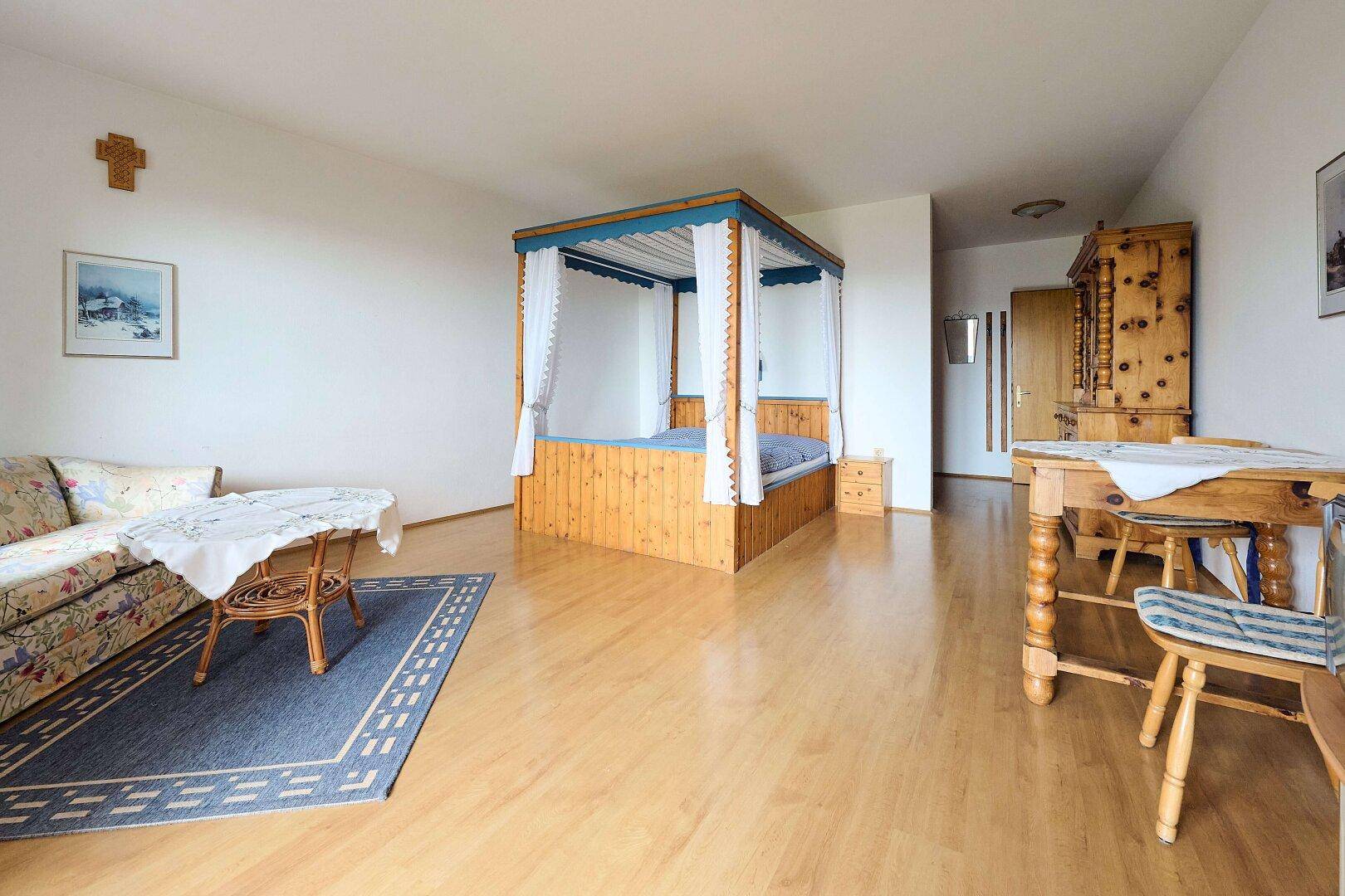 Geräumiges Schlafzimmer mit Himmelbett, Sofa und traditionellen Holzmöbeln.
