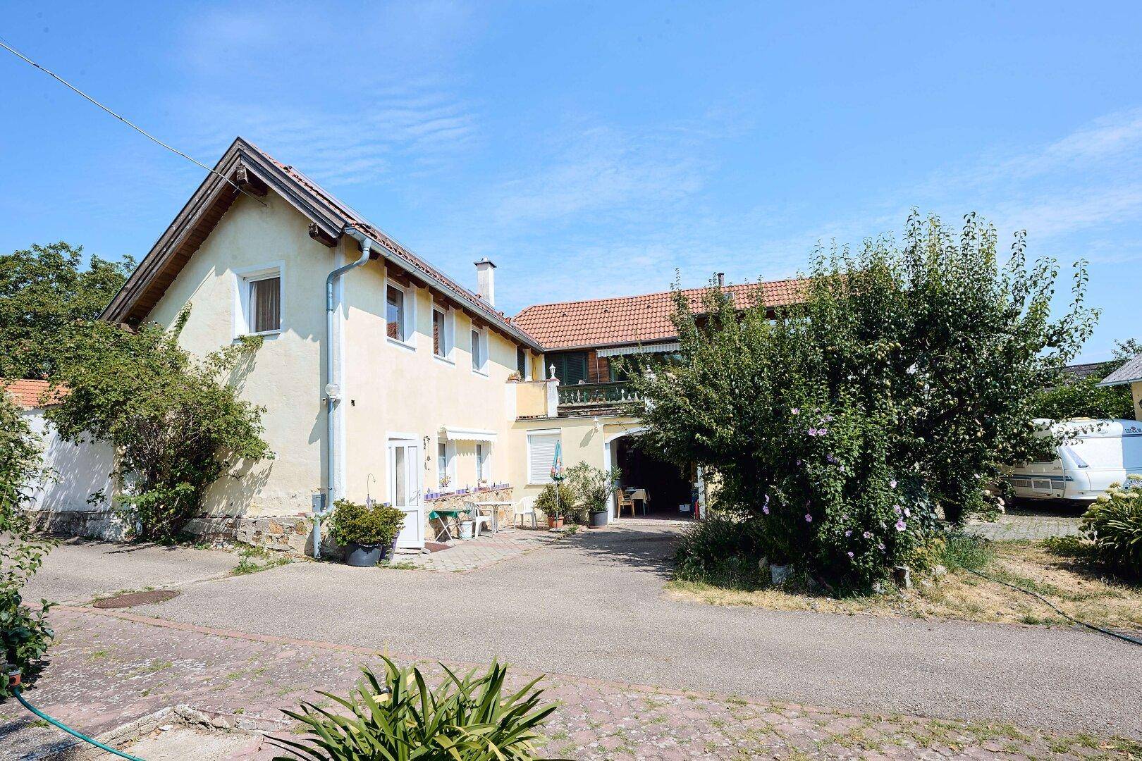 Rückansicht der Gebäude mit gepflasterter Zufahrt und einem Durchgang unter einem Balkon.