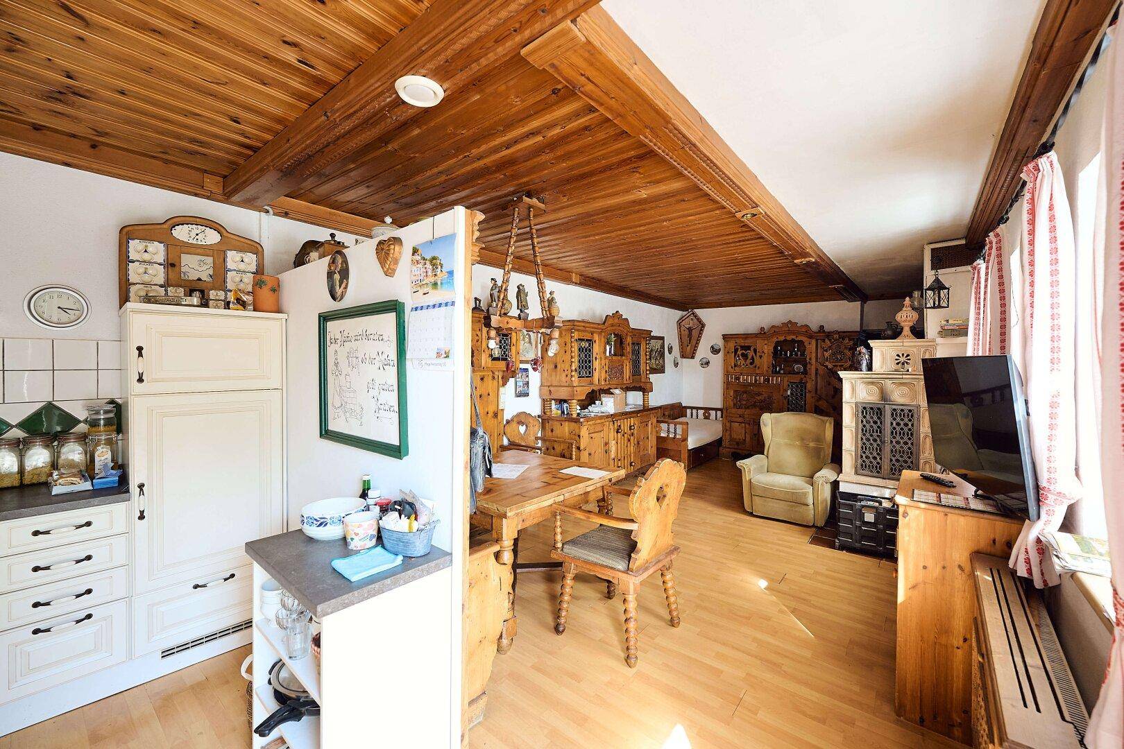 Rustikaler Wohn- und Essbereich mit Holzbalkendecke, Kachelofen und traditionellen Möbeln.