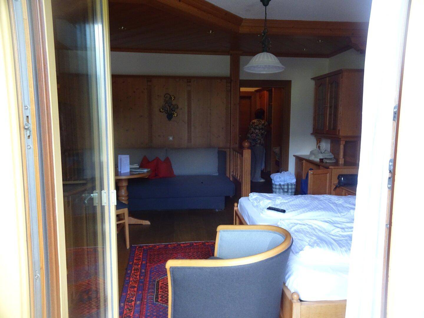 Schlafzimmer mit Holzwänden, Bett und Zugang zu einem Balkon oder einer Terrasse.