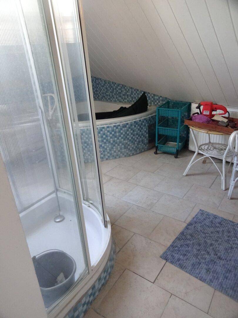 Badezimmer im Dachgeschoss mit Dusche, Badewanne und blauen Mosaikfliesen.