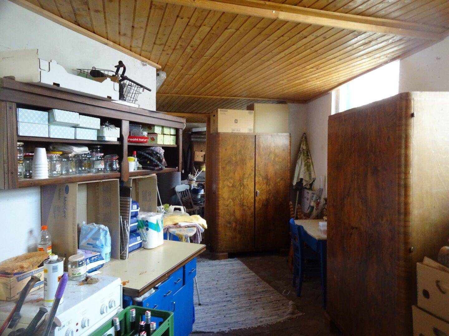 Abstellraum mit Holzdecke, alten Schränken und verschiedenen Haushaltsgegenständen.