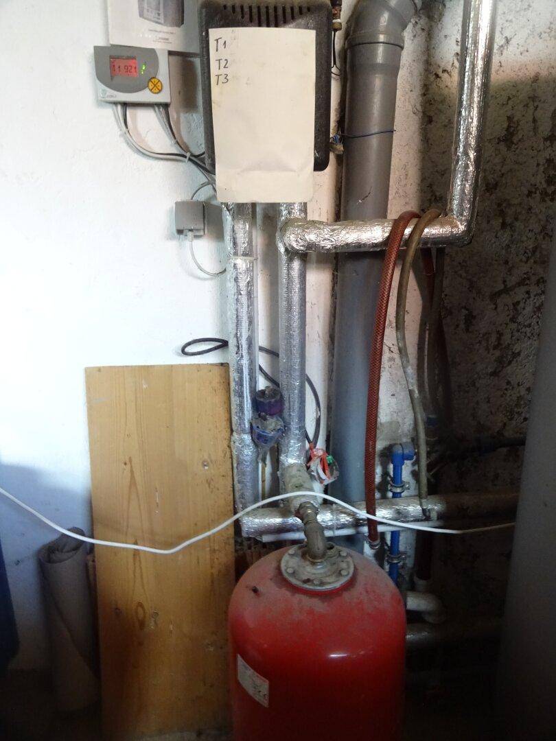 Technikraum mit isolierten Rohren, einem Ausdehnungsgefäß und Wandinstallationen.