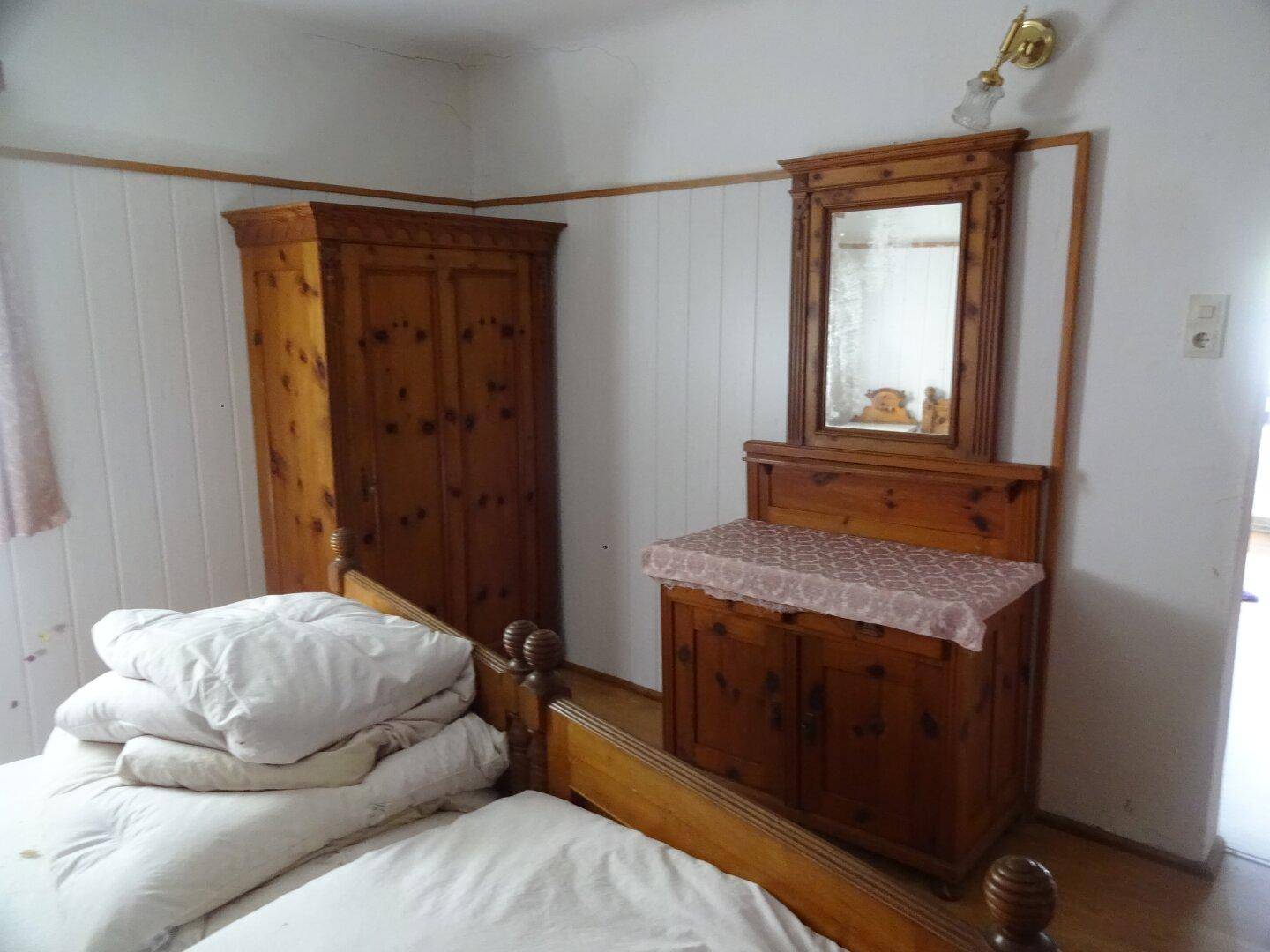 Rustikales Schlafzimmer mit Holzschrank, Frisiertisch und traditionellem Holzbett.