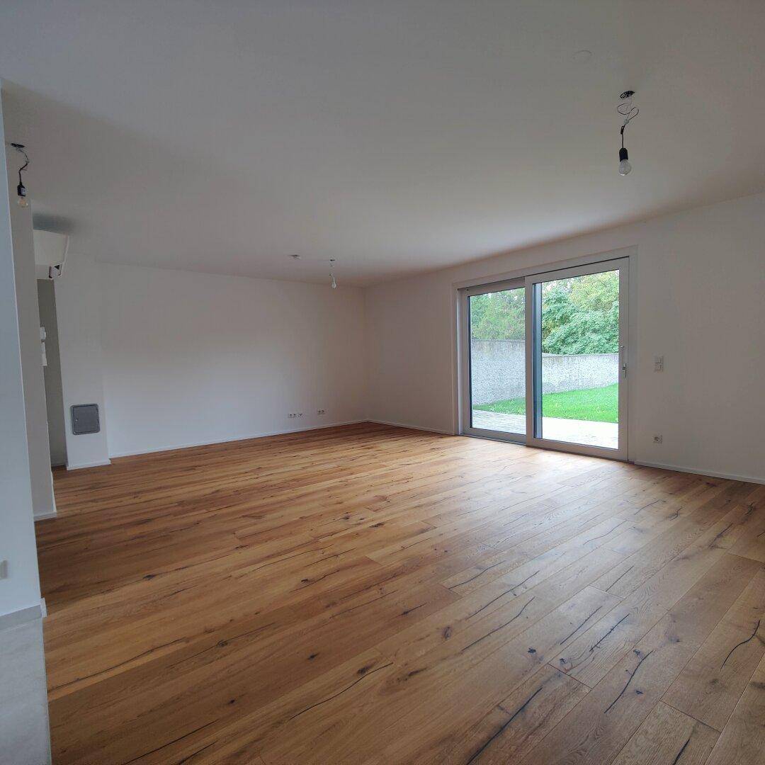 Heller Wohnbereich mit Holzboden und großer Schiebetür zum Garten, bietet viel Tageslicht.