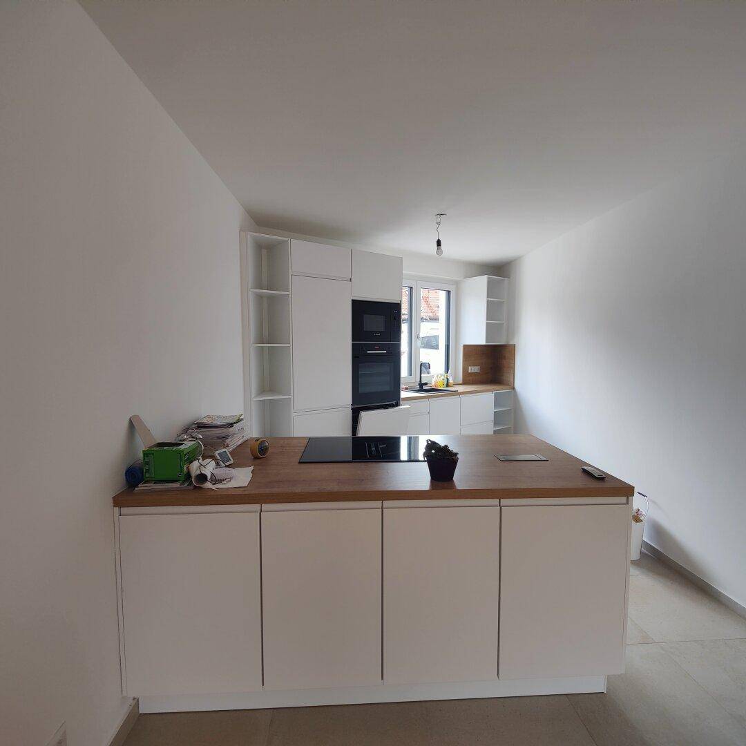Moderne Einbauküche mit weißer Kücheninsel, Holz-Arbeitsplatte und integrierten Geräten.