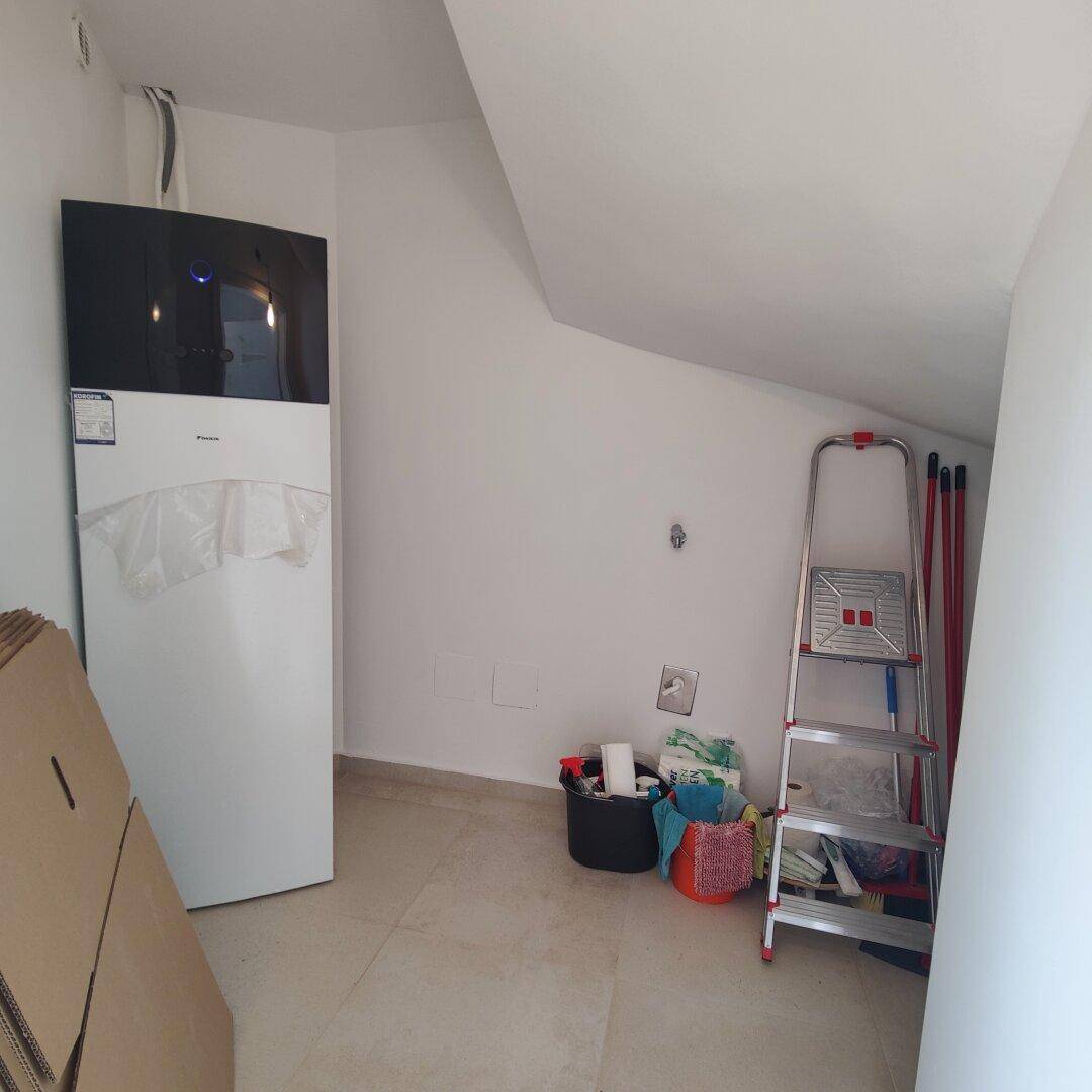 Hauswirtschaftsraum mit Wärmepumpe, Dachschräge und Stauraum für Reinigungsgeräte.
