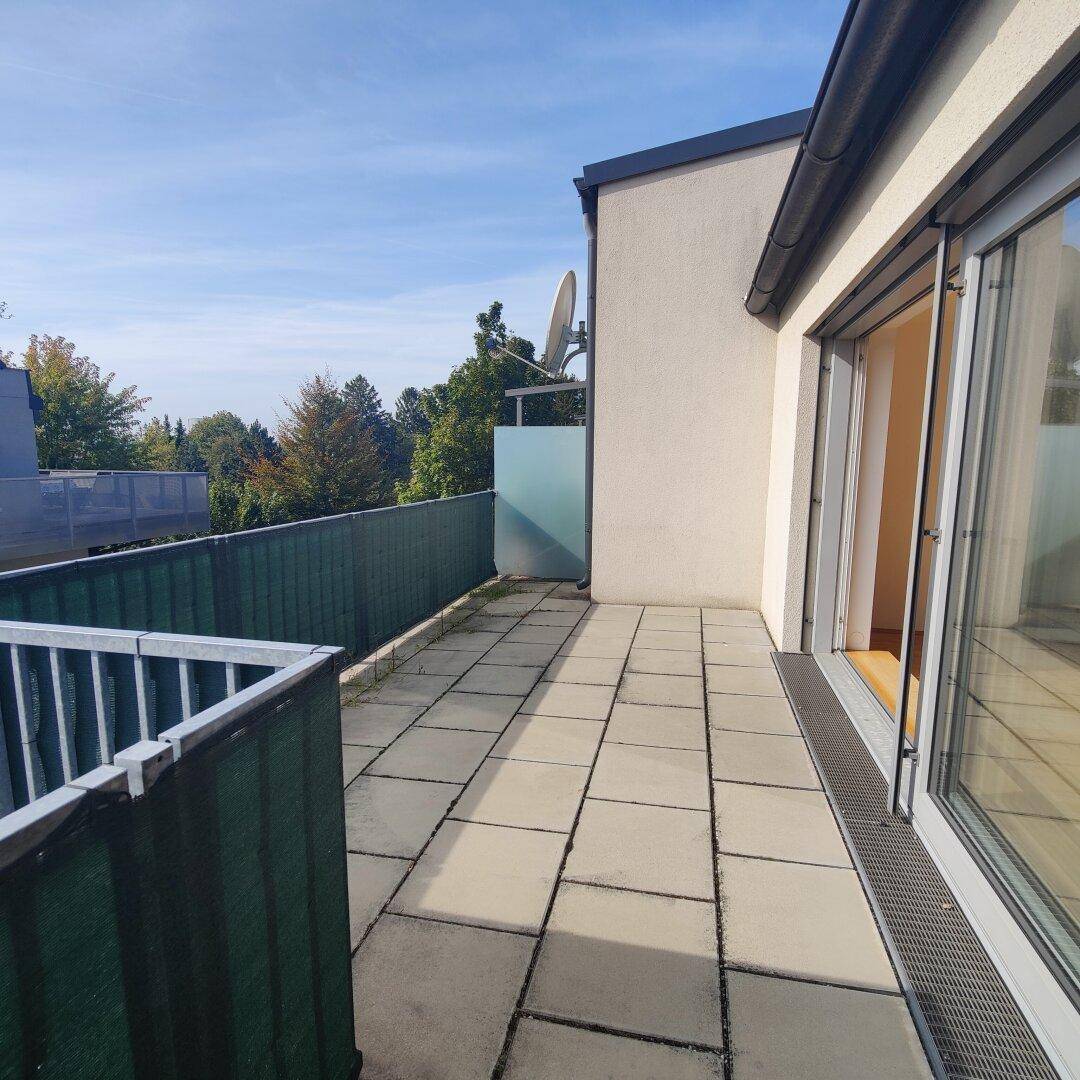 Geräumige Außenterrasse mit Fliesenboden und Blick ins Grüne, ideal für Entspannung im Freien.