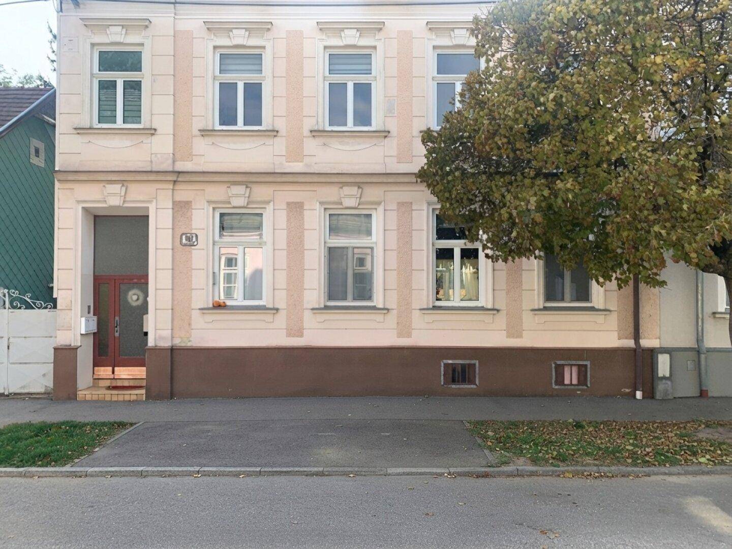 Frontansicht eines traditionellen Wohnhauses mit mehreren Etagen und einer hellen Fassade.