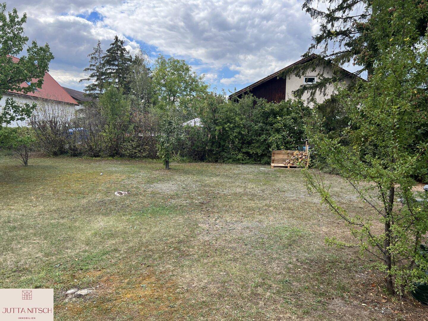 Weitläufiger Garten mit Rasenfläche und jungen Bäumen, bereit für individuelle Gestaltung.
