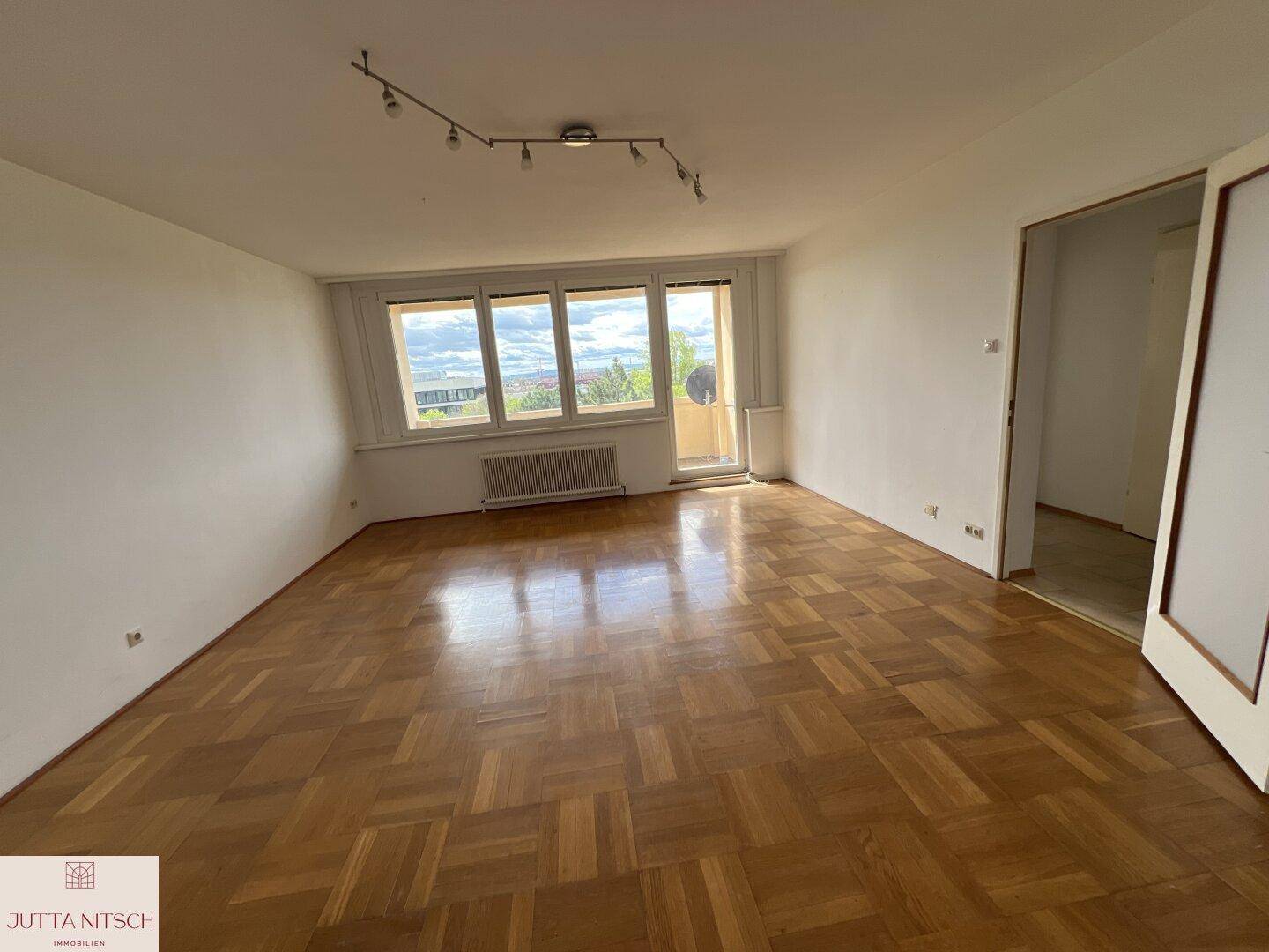 Geräumiges Wohnzimmer mit klassischem Parkettboden und viel Tageslicht.