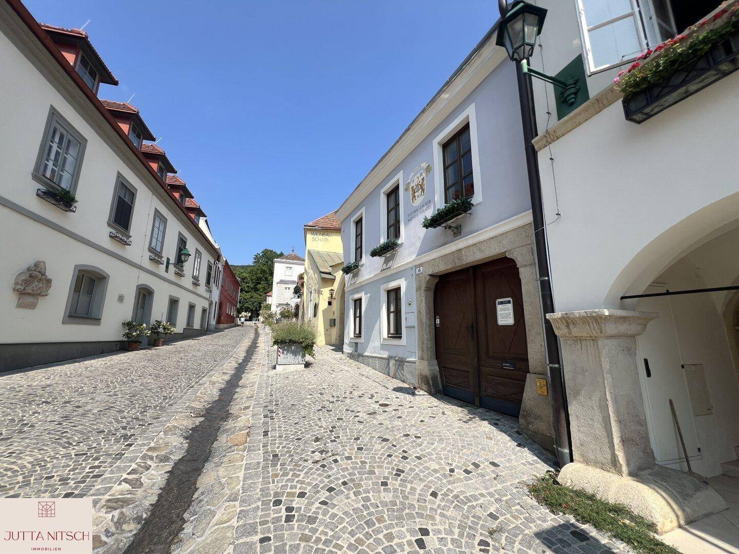 Historische Kopfsteinpflasterstraße mit charmanten Gebäuden und einer traditionellen Straßenlaterne.