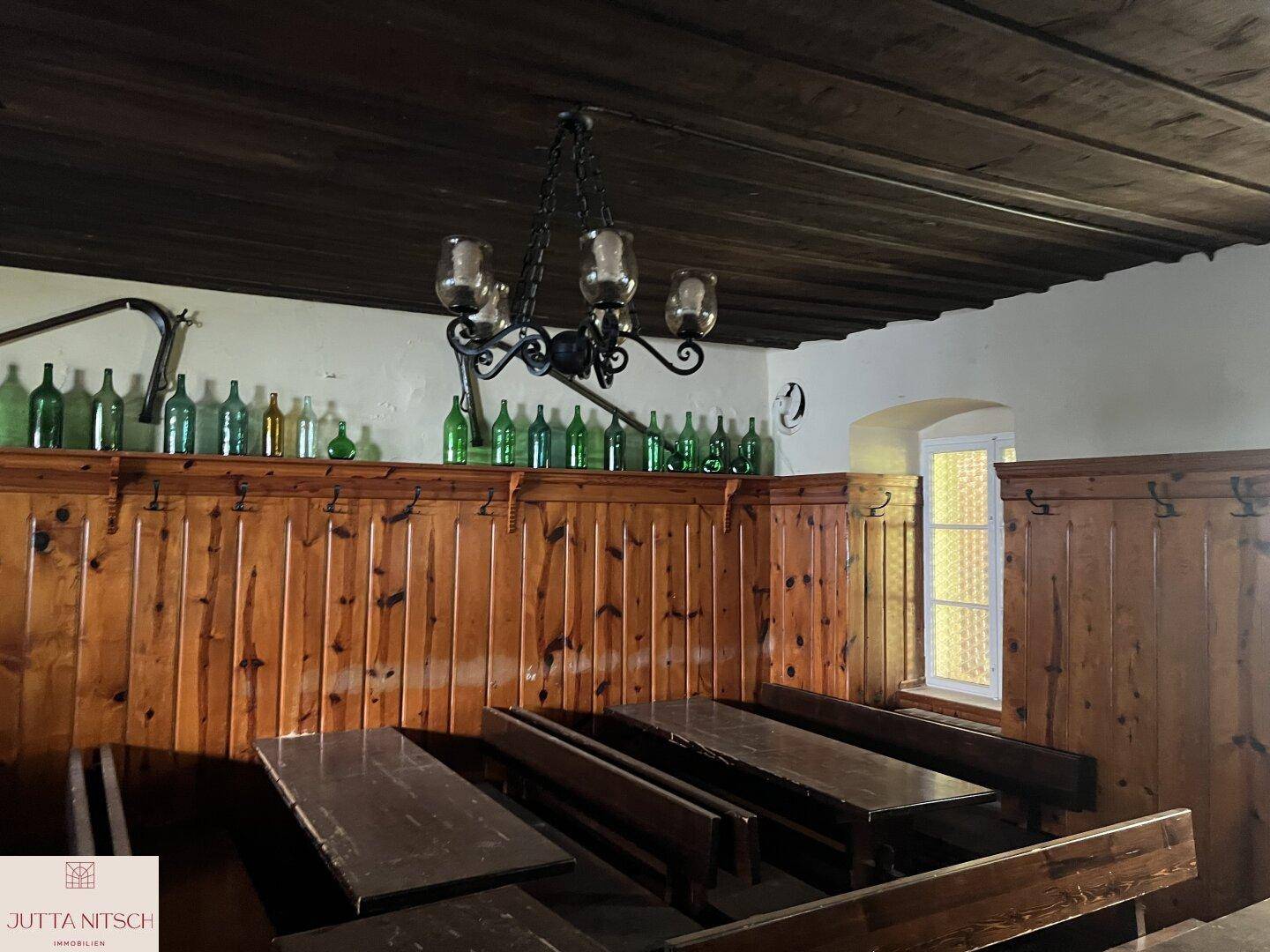 Gemütlicher, rustikaler Essbereich mit Holztäfelung, dunklen Möbeln und einem kleinen Fenster.
