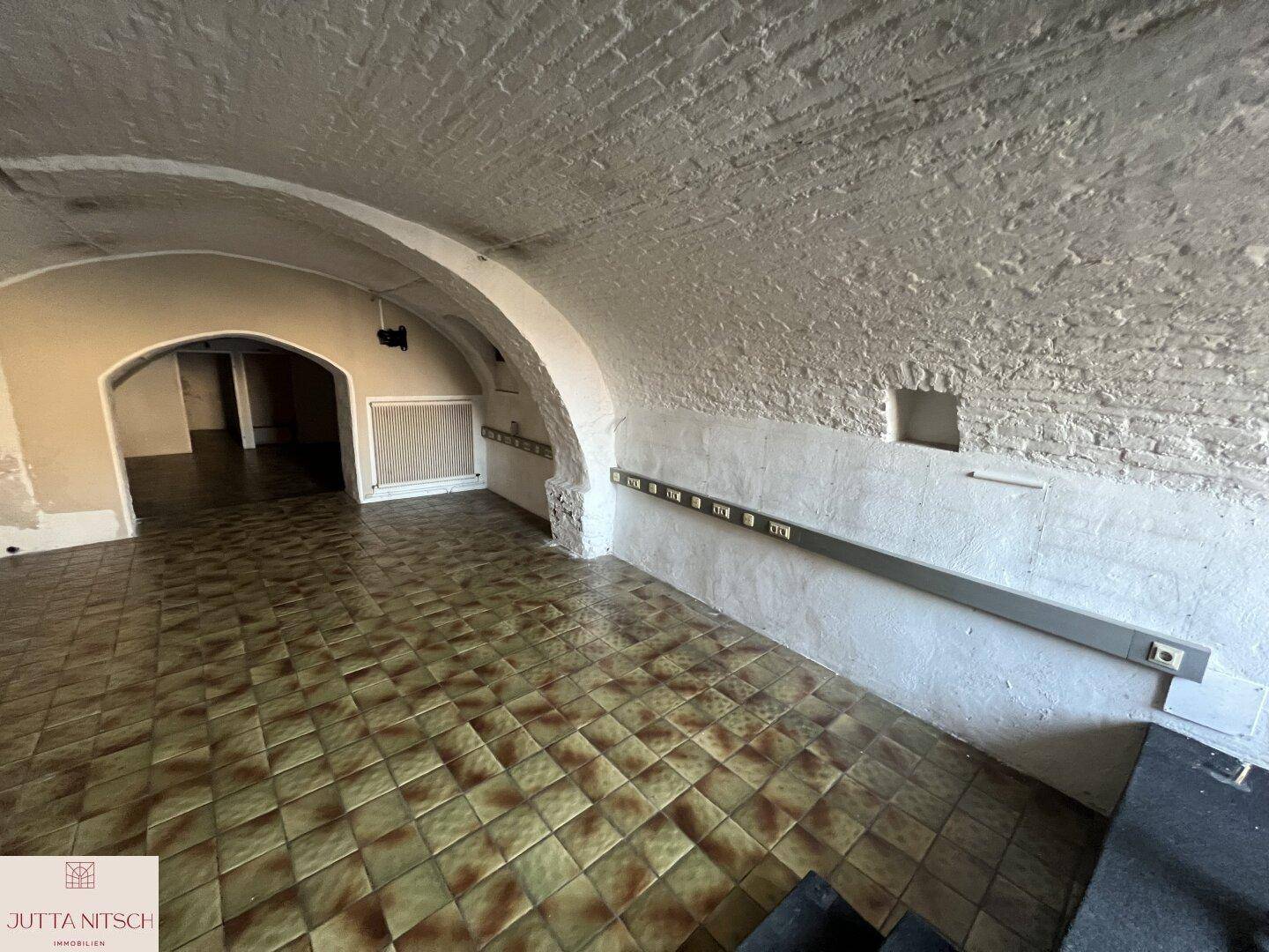 Gewölbekeller mit traditionellen Fliesen und freiliegenden Ziegeln an der Decke, ideal für Lagerung.