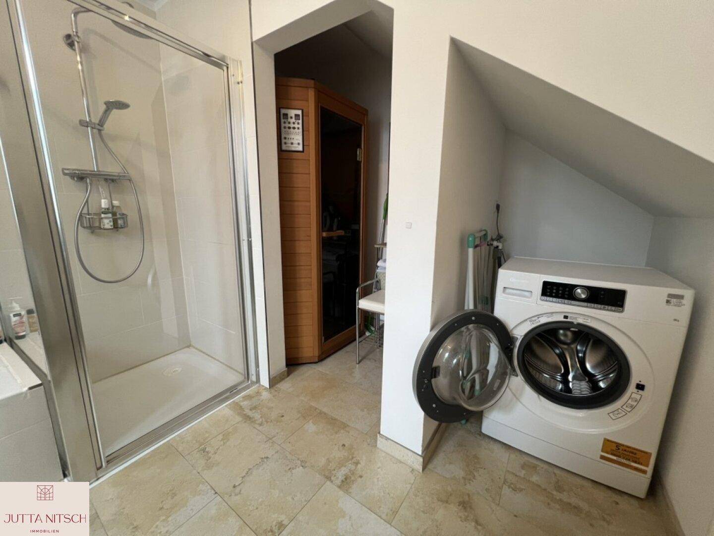 Praktischer Bereich mit Duschkabine, Waschmaschine und integrierter Sauna.