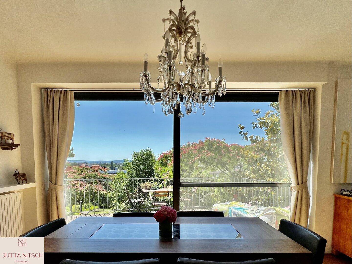 Eleganter Essbereich mit Kronleuchter und großen Fenstern, die einen weiten Blick in die Landschaft bieten.